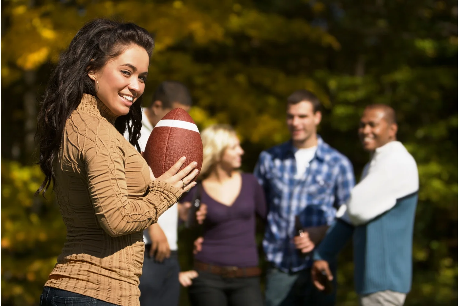 Woman Holding Football with Tailgate in Background