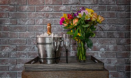 flowers in vase next to wine and 2 glasses