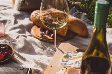 Glass of wine on picnic blanket with bread and a book